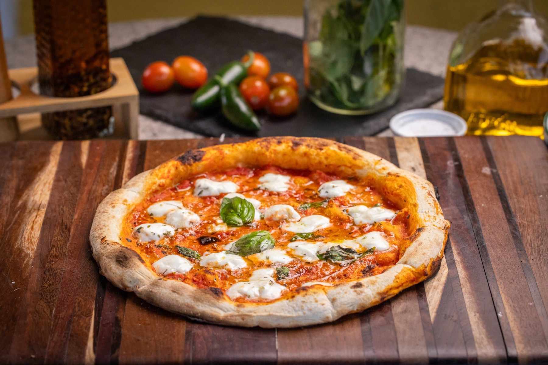 Pizza Búfala a la leña con mozzarella de búfala y albahaca fresca sobre tabla de madera